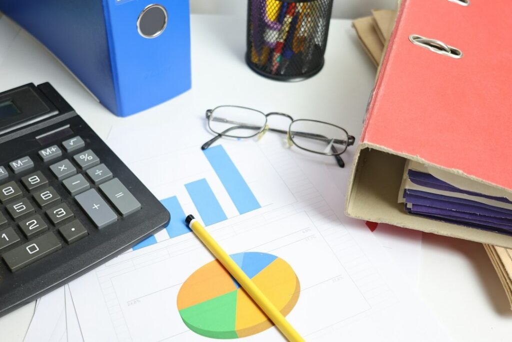 Mesa de trabajo con calculadora, gráficos de rendimiento y documentos para analizar visitas y conversiones de un blog