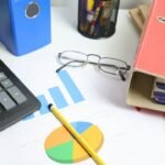 Mesa de trabajo con calculadora, gráficos de rendimiento y documentos para analizar visitas y conversiones de un blog