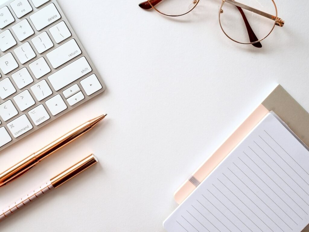 Cuaderno con hojas rayadas, bolígrafo y gafas para ilustrar la comprobación editorial de textos creados con inteligencia artificial
