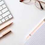 Cuaderno con hojas rayadas, bolígrafo y gafas para ilustrar la comprobación editorial de textos creados con inteligencia artificial
