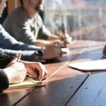 Personas reunidas alrededor de una mesa de trabajo, imagen ilustrativa de deliberación colectiva; no muestra al equipo de Anthropic ni a beneficiarios de su fondo