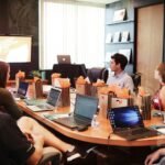 Reunión de trabajo con varias personas y ordenadores portátiles, imagen ilustrativa de las expectativas sobre inteligencia artificial y empleo