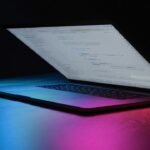 Portátil iluminado con luces de neón, imagen destacada de IA VIRAL y sus 101 prompts para crear contenido