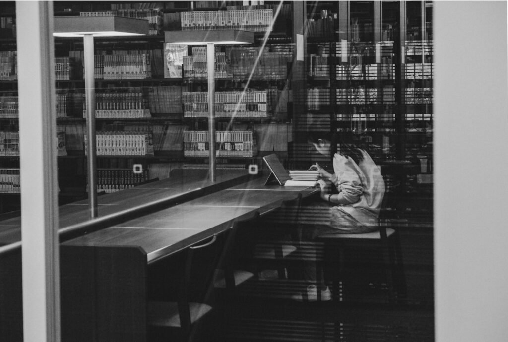 Investigadora revisa documentos científicos con un portátil en una biblioteca