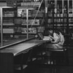 Investigadora revisa documentos científicos con un portátil en una biblioteca