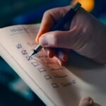 Mano que marca tareas en una lista de comprobación sobre un escritorio, símbolo de evaluación y control de calidad de agentes de inteligencia artificial