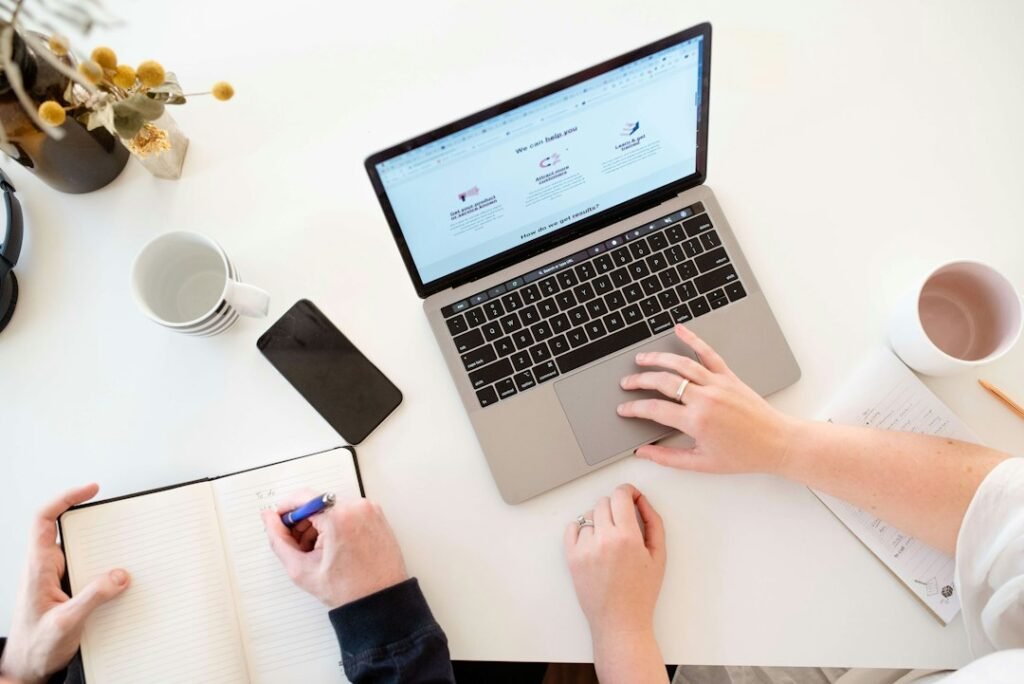 Mesa de trabajo con ordenador portátil, teléfono y cuaderno para planificar marketing digital y herramientas de inteligencia artificial