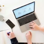 Mesa de trabajo con ordenador portátil, teléfono y cuaderno para planificar marketing digital y herramientas de inteligencia artificial