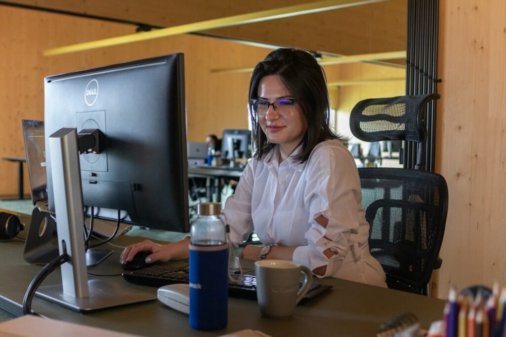 Profesional con gafas utilizando un ordenador en su mesa de oficina para ilustrar atención al cliente y protección de la privacidad con asistentes de inteligencia artificial