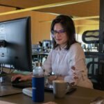 Profesional con gafas utilizando un ordenador en su mesa de oficina para ilustrar atención al cliente y protección de la privacidad con asistentes de inteligencia artificial
