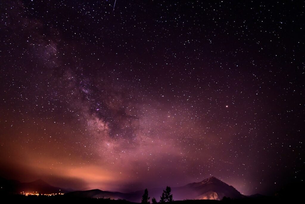 Vía Láctea sobre el paisaje nocturno en tonos púrpura, fotografía ilustrativa del artículo sobre el mapa ultravioleta del cielo creado con Claude Science. No es una imagen del mapa científico.